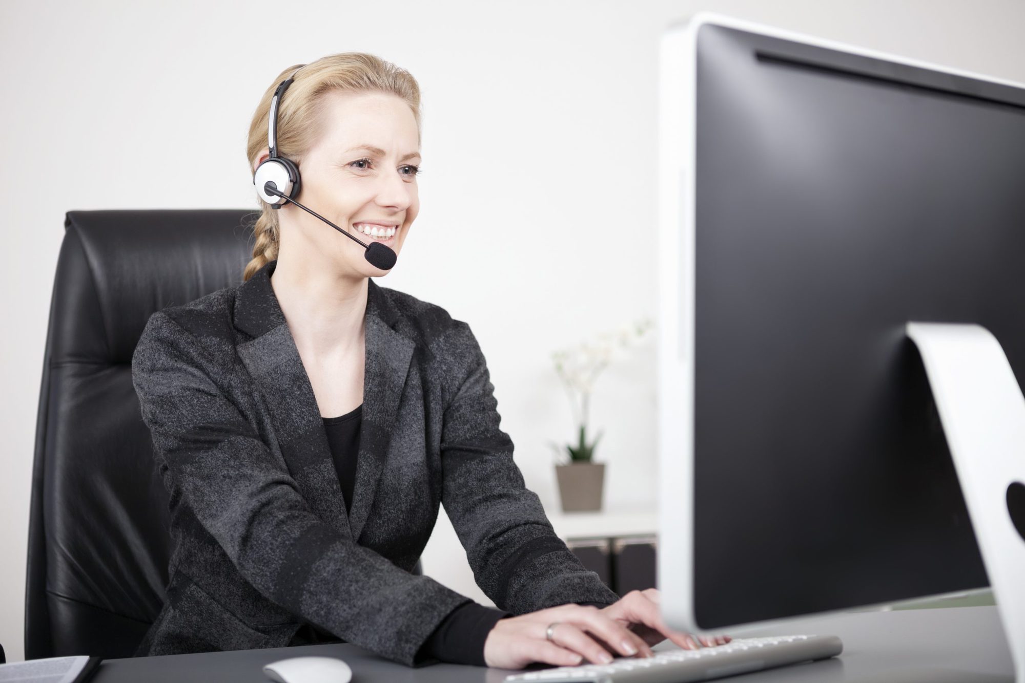 Smiling Female Customer Service Representative Typing on Computer While Sitting at her Office.